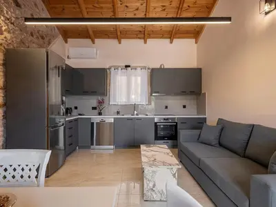 a living room with a couch and a kitchen at To Petrino Stone Mountain Retreat with Private Pool in Rodhopós