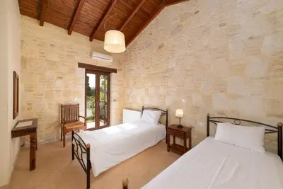 a bedroom with two beds and a stone wall at 3-Min Drive to Kalyves Beach, Stone Home with Private Pool in Armenoi Center in Arménoi