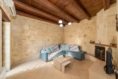 a living room with a couch and a tv at 3-Min Drive to Kalyves Beach, Stone Home with Private Pool in Armenoi Center in Arménoi