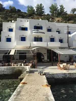 a large white building next to the water at Daskalogiannis Hotel in Loutro