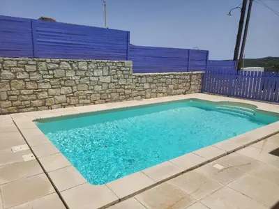 a swimming pool with a stone wall and a blue at Aphrodite villa in Darmarochori