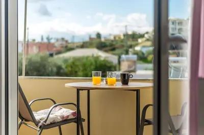 two glasses of orange juice on a table in front of a window at Cozy Apartment Next To The Beach In Almyrida -BY APOKORONAS VILLAS in Almirida