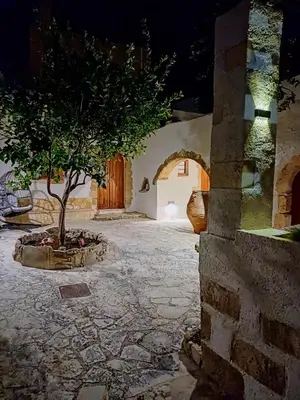 a building with a tree in the middle of a courtyard at Violetta Kaliviani room 1 in Kalivianí