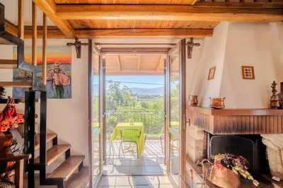 a living room with a fireplace and a balcony at Traditional Art House Armenoi in Arménoi