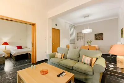 a living room with a couch and a room with a bed at Leda's Nea Chora Flat, Near Beach and Old Port in Chania Town
