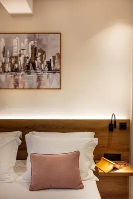 a bed with white pillows and a painting on the wall at Mystrali I in Galatás