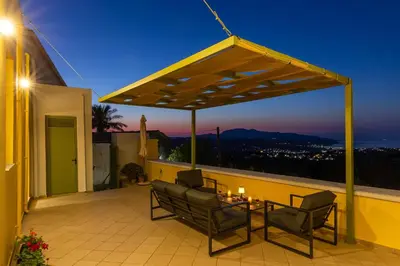 a patio with chairs and a table on a roof at The Yellow Veranda - Close to Ancient Olive Tree of Vouves in Áno Voúvai