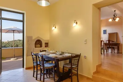 a dining room with a table and chairs and a balcony at The Yellow Veranda - Close to Ancient Olive Tree of Vouves in Áno Voúvai