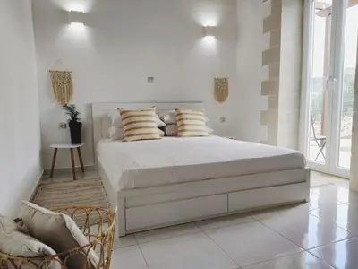 a white bedroom with a bed and a chair at Villa Naiades Traditional Cretan Stone House with private Pool and Garden in Chania in Arménoi