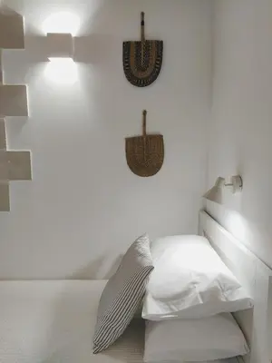 a bedroom with white walls and a bed with white pillows at Villa Naiades Traditional Cretan Stone House with private Pool and Garden in Chania in Arménoi