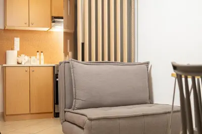 a chair sitting in a room with a kitchen at Sea & City - Luxury Maisonette Steps from the Beach with Private Terrace in Chania Town