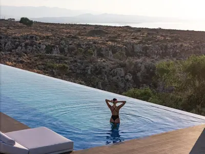 a woman is standing in the water at a swimming pool at Orus Villa in Chania Town