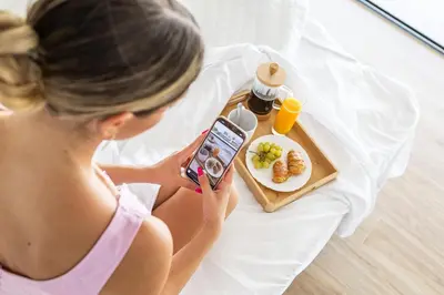 a woman sitting on a bed taking a picture of a plate of food at Orus Villa in Chania Town