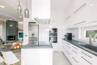 a kitchen with white cabinets and a counter top at Adriana Horizon Villa, Pool & Hillside View in Galatás