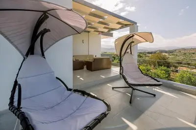 two chairs sitting on a balcony with a view at Adriana Horizon Villa, Pool & Hillside View in Galatás