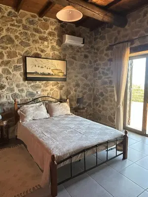 a bedroom with a bed with a stone wall at Villa Santouraki in Keramotí