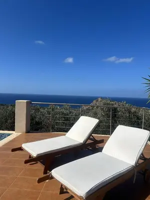 two white lounge chairs on a patio with the ocean at Villa Santouraki in Keramotí
