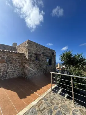 a stone house with a balcony and a blue sky at Villa Santouraki in Keramotí