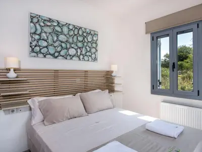 a white bedroom with a bed and a window at Holiday Home Villa vacanze Agave Creta con piscina privata by Interhome in Litsárdha
