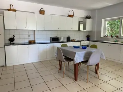 a kitchen with white cabinets and a table with chairs at Ellie's Kantanos in Kántanos