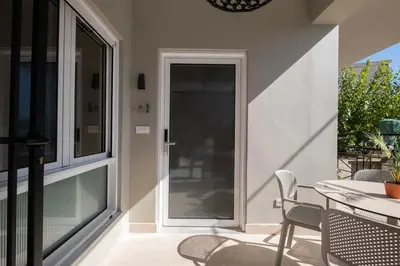a patio with a table and chairs and a glass door at Raviewha Luxury Apartments 3 in Ravdhoúkha