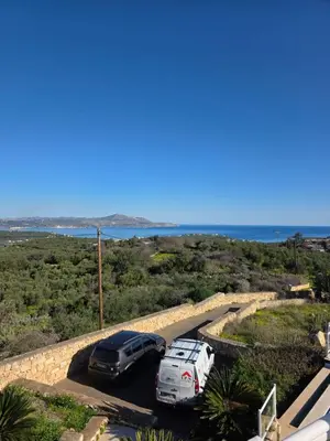 two cars parked in a parking lot near the ocean at Villa Anna Gaia In Tzivaras in Tsivarás