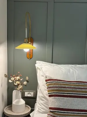 a bed with a pillow and a lamp and a vase with flowers at Cellar - Shared Pool & Nature Views in Spiliá
