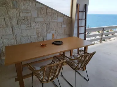 a wooden table and two chairs on a balcony with the ocean at Meteoron Platanias in Plataniás