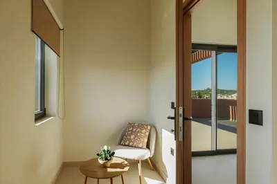 a room with a chair and a table and a door at Madre Tierra Boutique Villas 3 & 4 in Potistíria