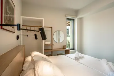 a white bedroom with a bed and a mirror at Deux Olives Luxury Villa in Maleme