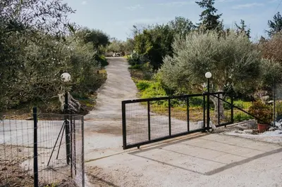 a gate leading down a dirt road with trees at Olive Dome, Luxury Glamping Dome in Crete in Gavalochori