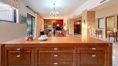 a large wooden island in a kitchen with a living room at Lithos Serenity in Argoulidhés