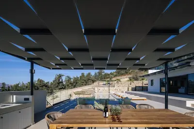 a dining room with a table and a view of a pool at Villa Maninee-Bespoke Villa-Pool -BBQ-Seaview in Chania Town
