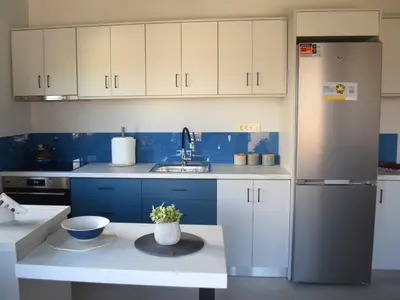 a kitchen with blue and white cabinets and a refrigerator at Modern Central Apartment - 400m to Beach in Kissamos