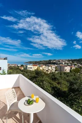 a white table and chairs on a balcony with a view at Almyrida Bayview VII - BY APOKORONAS VILLAS in Almirida
