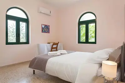 a bedroom with a large white bed with two windows at 5-bedroom Country House in Crete - Olive Grove Retreat in Nerokhórion
