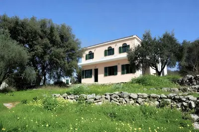 a large house with a stone wall in a field at 5-bedroom Country House in Crete - Olive Grove Retreat in Nerokhórion