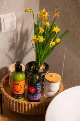 a vase of yellow flowers on a table next to a toilet at 3 Sails - 2BR on Venetian Harbour with Balcony in Chania Town