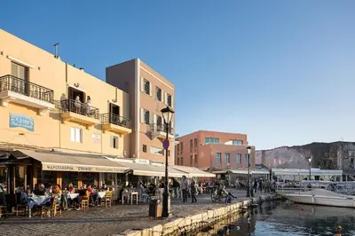 a group of people sitting at tables near a canal at 3 Sails - 2BR on Venetian Harbour with Balcony in Chania Town