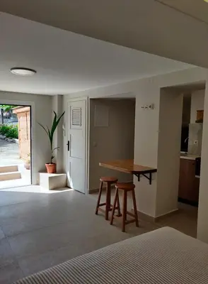a room with a table and chairs and a kitchen at Vrahakia Apartment 1 in Marina Galatas in Galatás