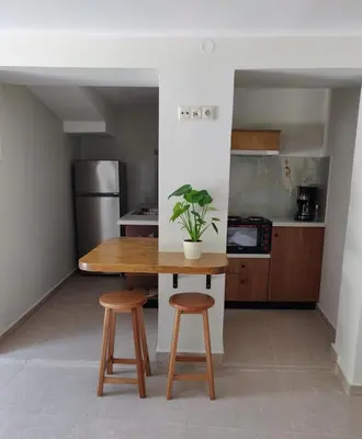 a kitchen with a wooden table and two stools at Vrahakia Apartment 1 in Marina Galatas in Galatás