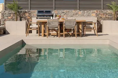 a dining table and chairs next to a swimming pool at Casa Viento in Ravdhoúkha
