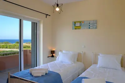 two beds in a bedroom with a view of the ocean at Sofoklis Apts in Stalos
