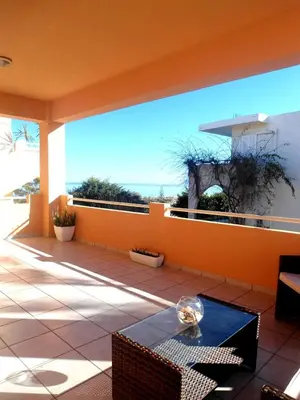 a balcony with an orange wall and a table at Sofoklis Apts in Stalos