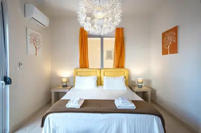 a bedroom with a bed with a chandelier at Kalyves Sand- Beach front apartment in Kalyves