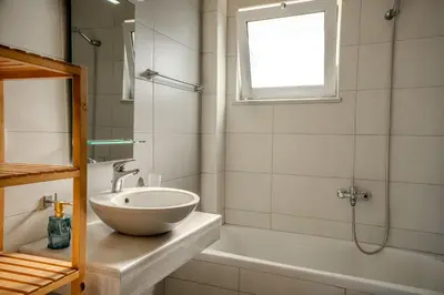 a bathroom with a sink and a tub and a window at Kalyves Sand- Beach front apartment in Kalyves