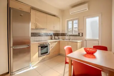 a kitchen with a refrigerator and a table with red chairs at Kalyves Sand- Beach front apartment in Kalyves