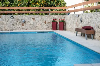 a swimming pool with a bench next to a stone wall at Villa Casa di Verde in Patellárion