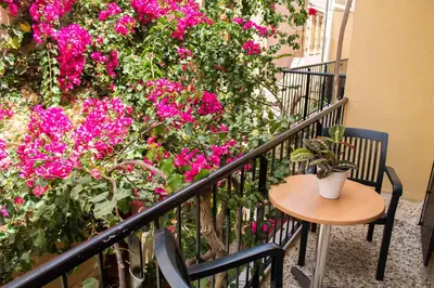 a table and chairs on a balcony with pink flowers at Iason Studios in Chania Town