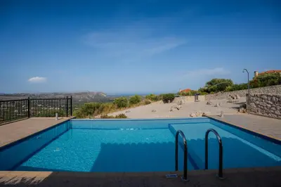 a blue swimming pool with a beach in the background at Villa Petra- Panormic Sea view - Private Pool in Kalyves